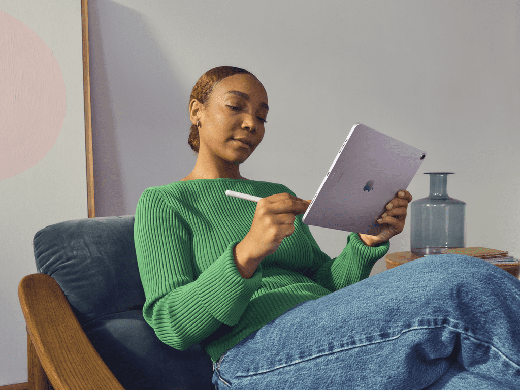 Mujer sentada en una silla, usando un iPad Air con un Apple Pencil.